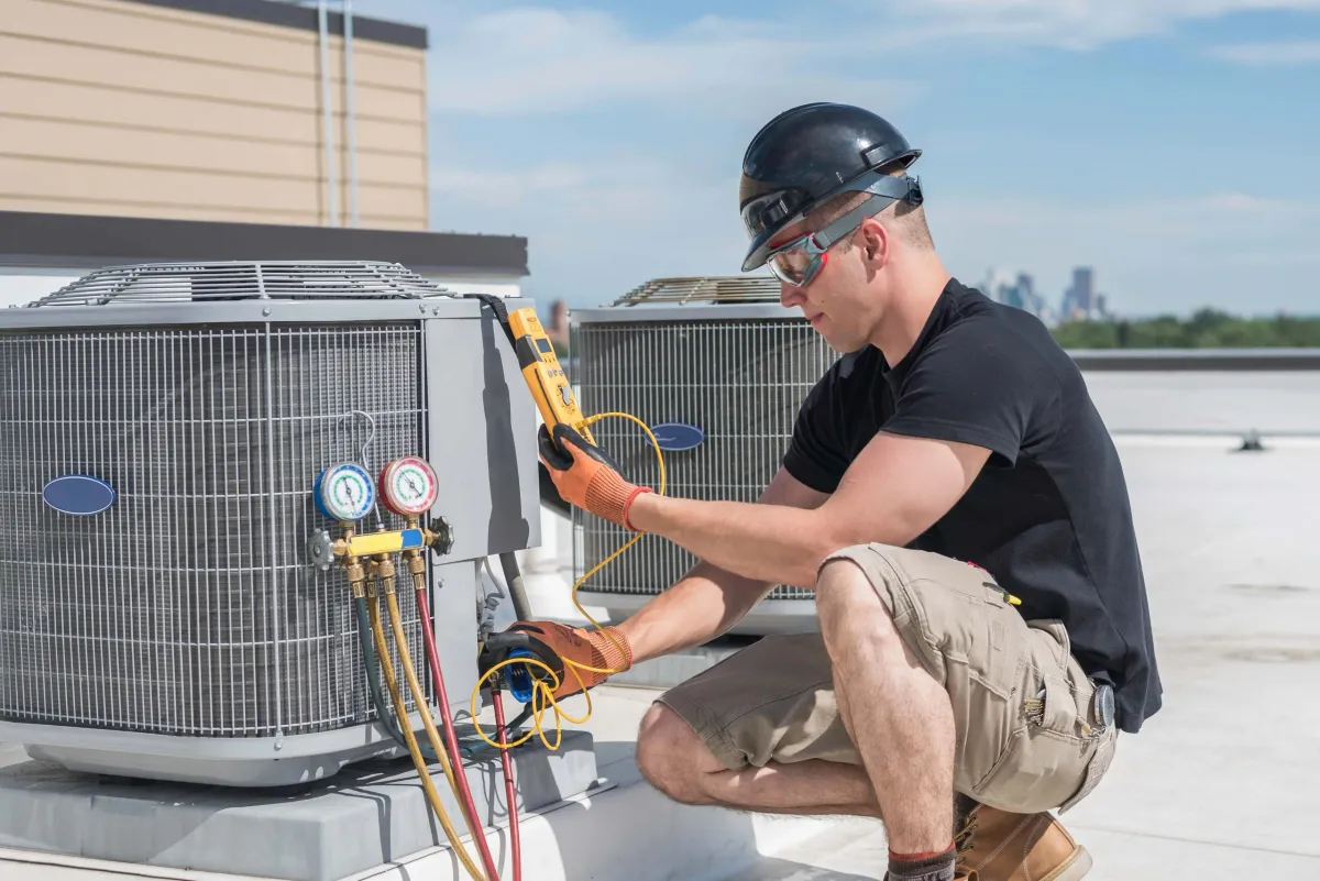 Professional HVAC technician servicing outdoor AC unit on residential job site