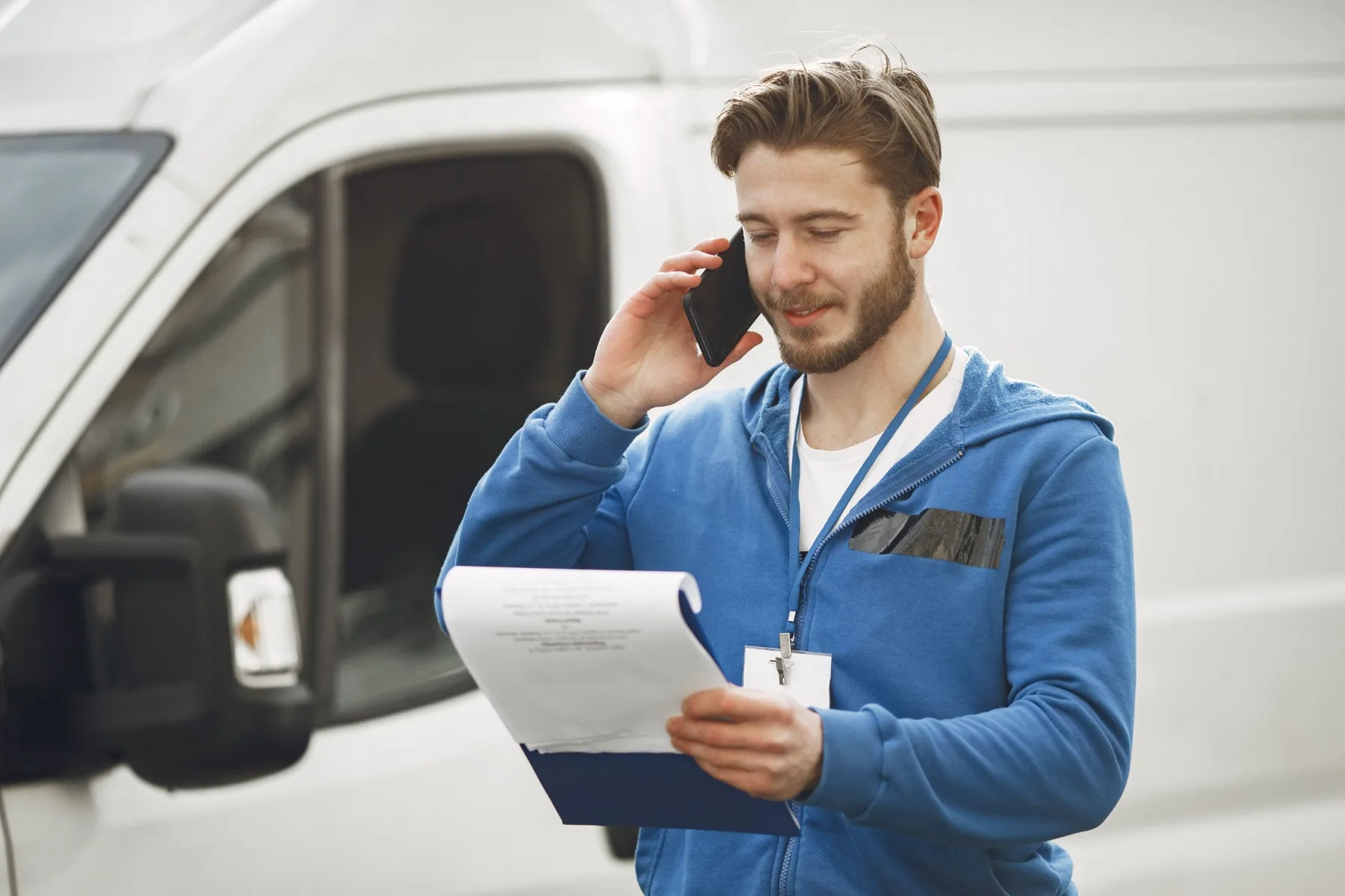 A service contractor taking a phone call beside his work van